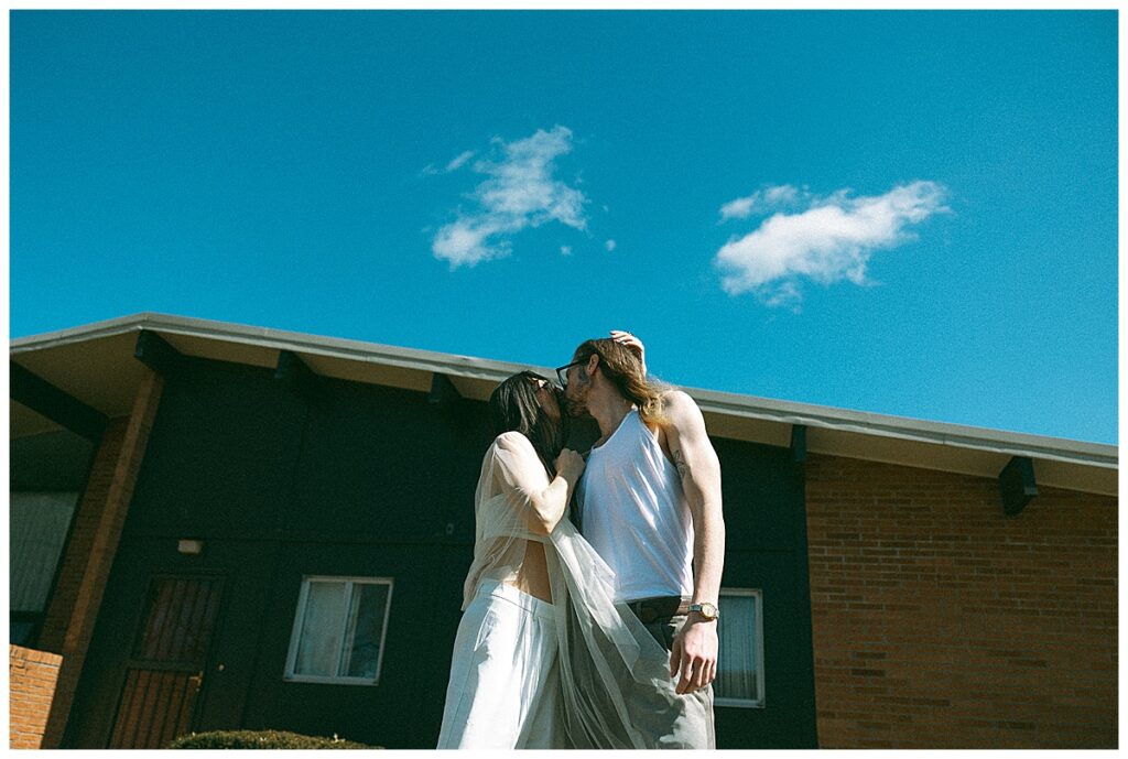 modern engagement photos kissing in retro clothes in front of seventies house